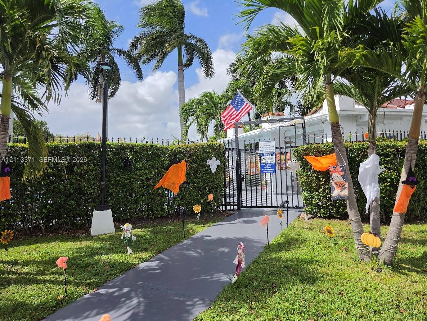9439 Fontainebleau Boulevard, #104, Miami, Miami, FL 33172 Gated entrance with a paved walkway, manicured hedging, and mature palm trees