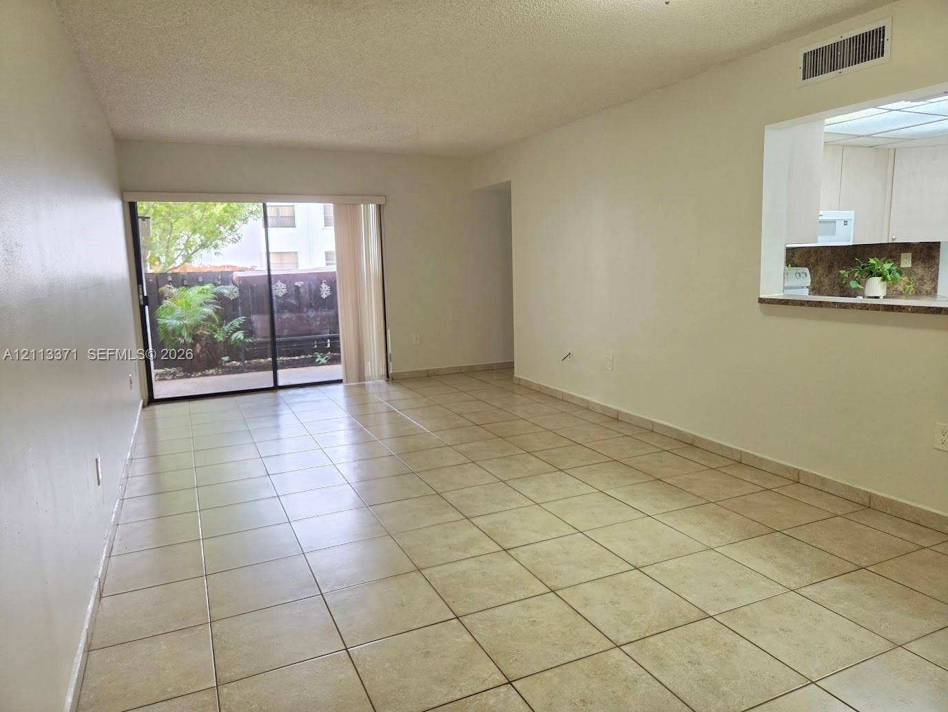 9439 Fontainebleau Boulevard, #104, Miami, Miami, FL 33172 Neutral tile flooring, sliding glass door with external patio access, and a service pass-through opening