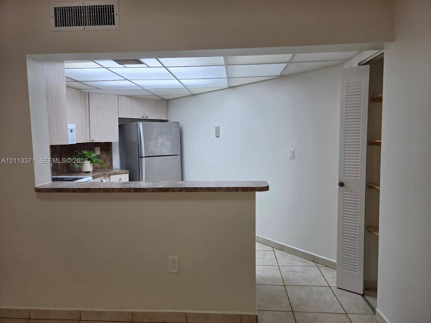 9439 Fontainebleau Boulevard, #104, Miami, Miami, FL 33172 Kitchen featuring light wood-finish cabinetry, a pass-through counter, stainless steel refrigerator, tile flooring, and built-in pantry shelving