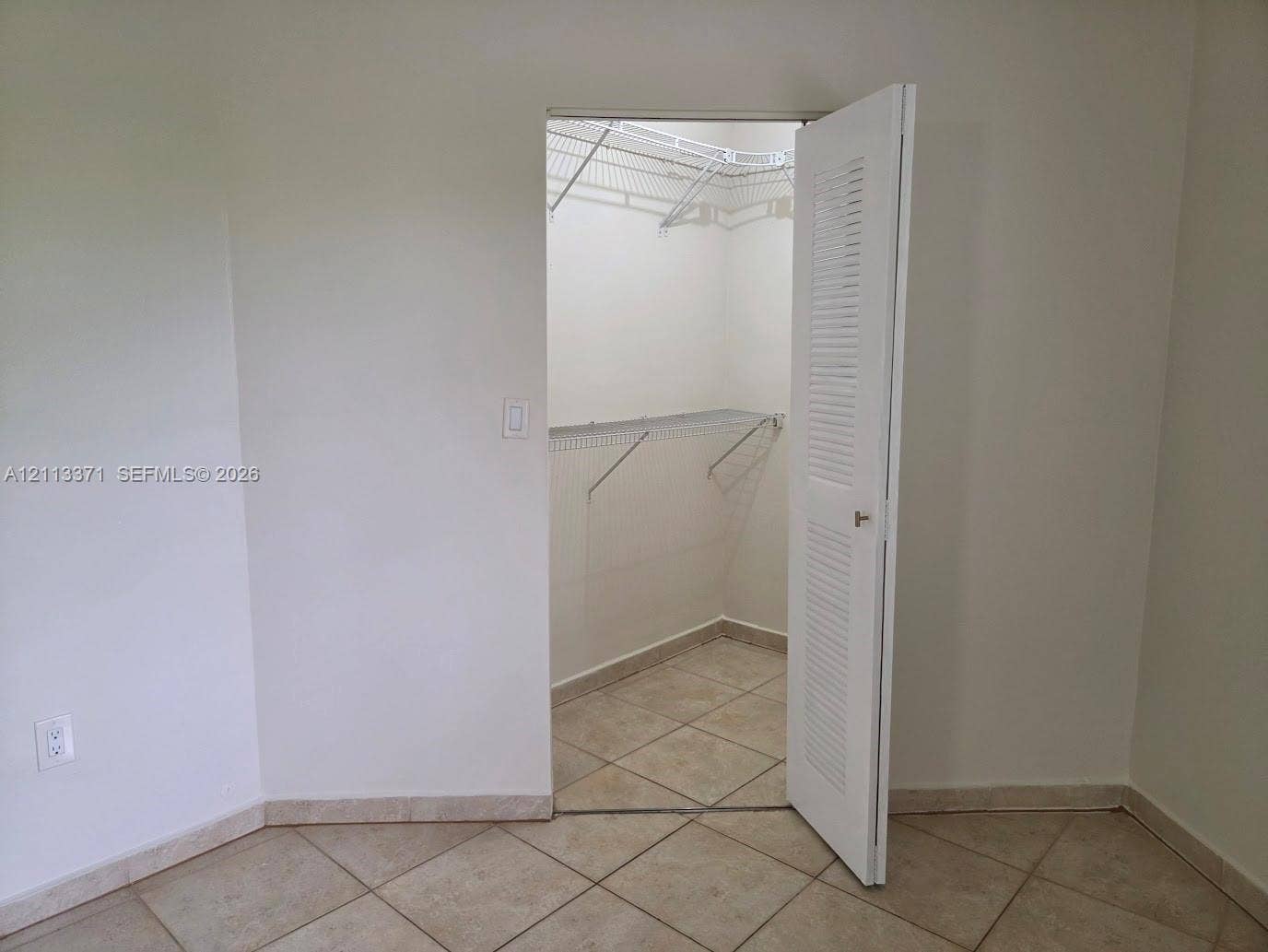 9439 Fontainebleau Boulevard, #104, Miami, Miami, FL 33172 Walk-in closet featuring white louvered door, tile flooring, and built-in wire shelving