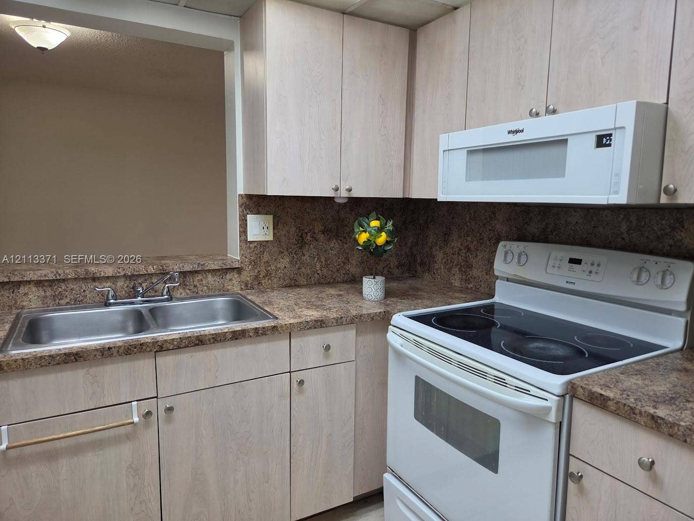 9439 Fontainebleau Boulevard, #104, Miami, Miami, FL 33172 Kitchen featuring light-finish wood cabinetry, laminate countertops, dual-basin stainless steel sink with metal faucet, electric range, and over-the-range microwave