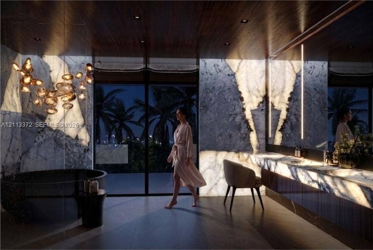 3312 NE 16th Court, Fort Lauderdale, FL 33305 Backlit stone wall cladding, floor-to-ceiling glass sliding doors, dark wood-finish ceiling, freestanding circular soaking tub, and built-in stone vanity with integrated lighting