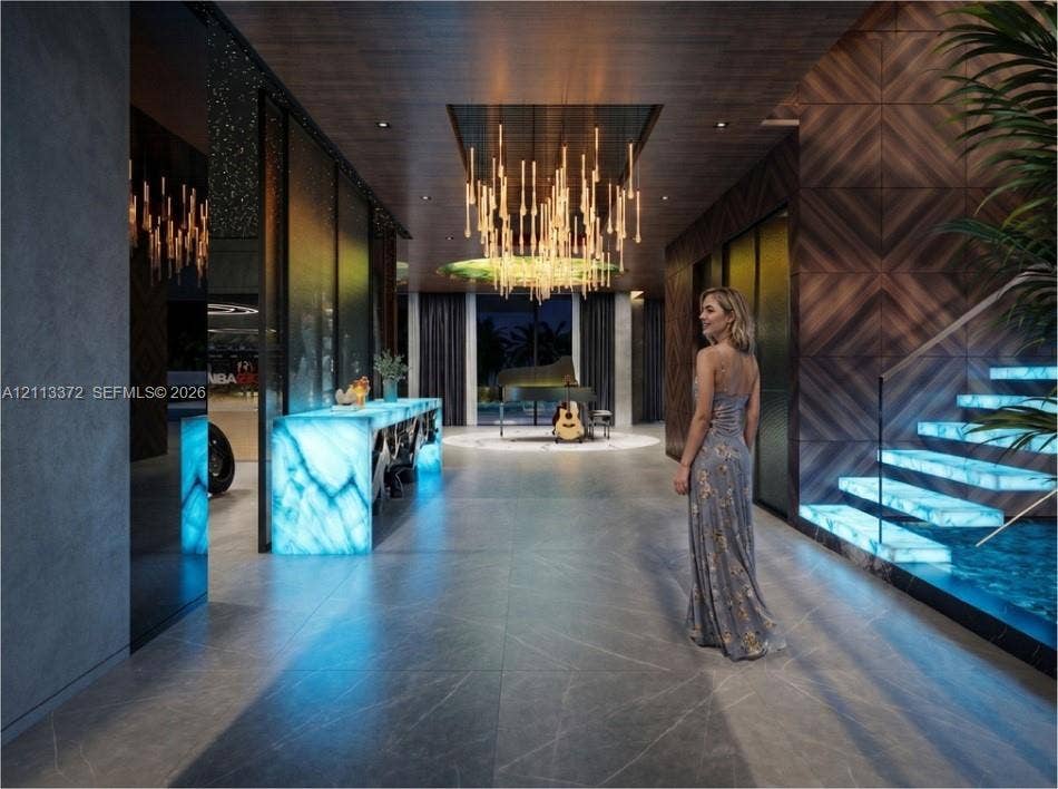 3312 NE 16th Court, Fort Lauderdale, FL 33305 Entry hall featuring large-format tile flooring, illuminated stone accents, wood-paneled walls, custom tiered chandelier, and a floating staircase with glass railings