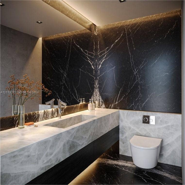 3312 NE 16th Court, Fort Lauderdale, FL 33305 Floating vanity with integrated sink, dark-veined stone wall cladding, wall-mounted dual-flush toilet, recessed LED accent lighting, and polished stone countertops