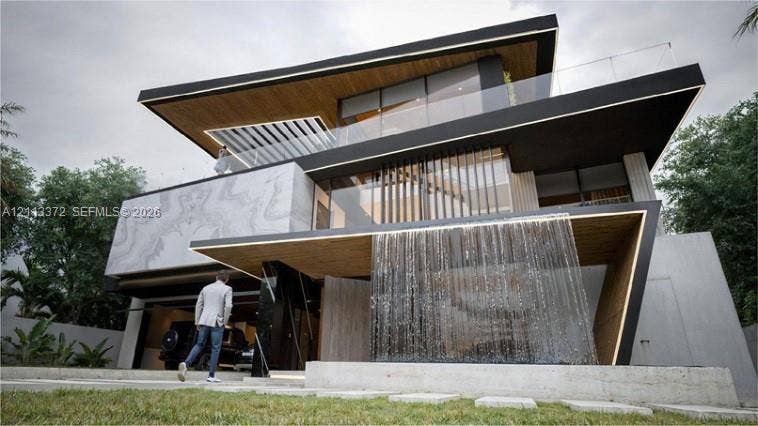 3312 NE 16th Court, Fort Lauderdale, FL 33305 Contemporary multi-level exterior featuring architectural stone cladding, wood-finish soffits, an integrated water feature, floor-to-ceiling glass paneling, and glass-railed balconies
