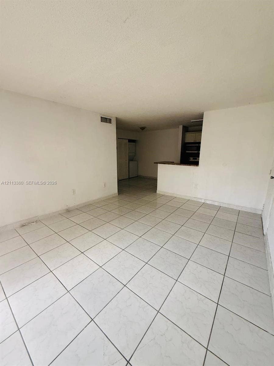 15610 SW 80th Street, #J-103, Miami, FL 33193 Open-concept interior featuring light-toned tile flooring and a kitchen breakfast bar with stone-surface countertop