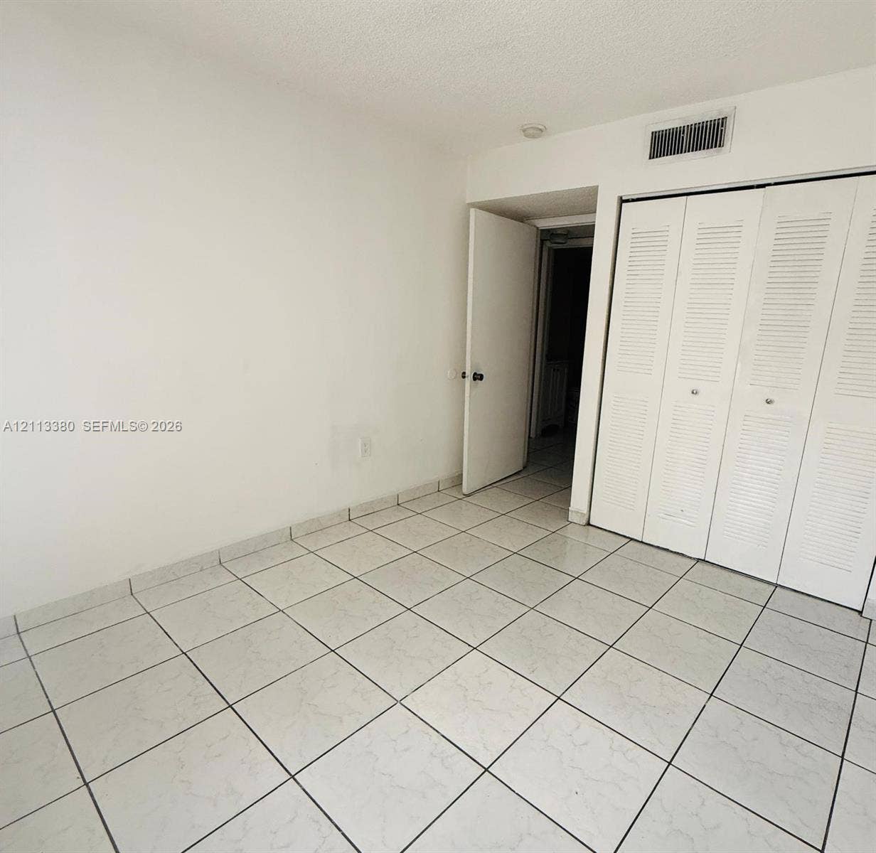 15610 SW 80th Street, #J-103, Miami, FL 33193 Neutral-toned ceramic floor tiling and full-height closet featuring white louvered bifold doors