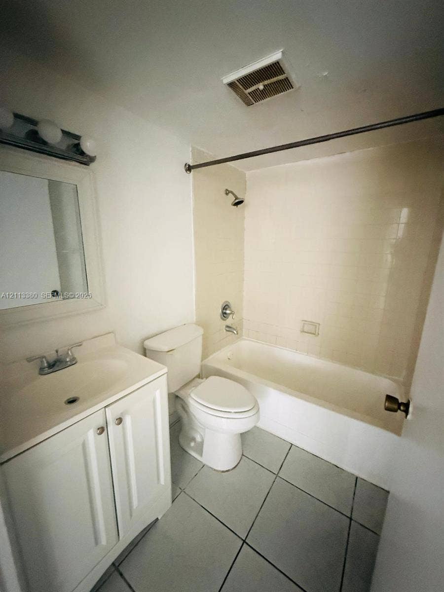 15610 SW 80th Street, #J-103, Miami, FL 33193 Bathroom featuring a white vanity cabinet, ceramic tile flooring, a tub and shower combination with tile surround, and a wall-mounted vanity mirror with integrated light fixture