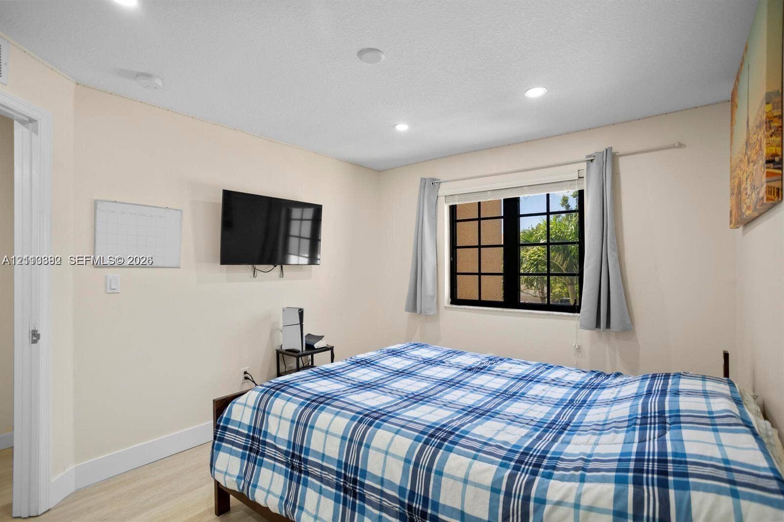 Room featuring light-toned wood-finish flooring, recessed lighting, and a multi-pane window with black framing