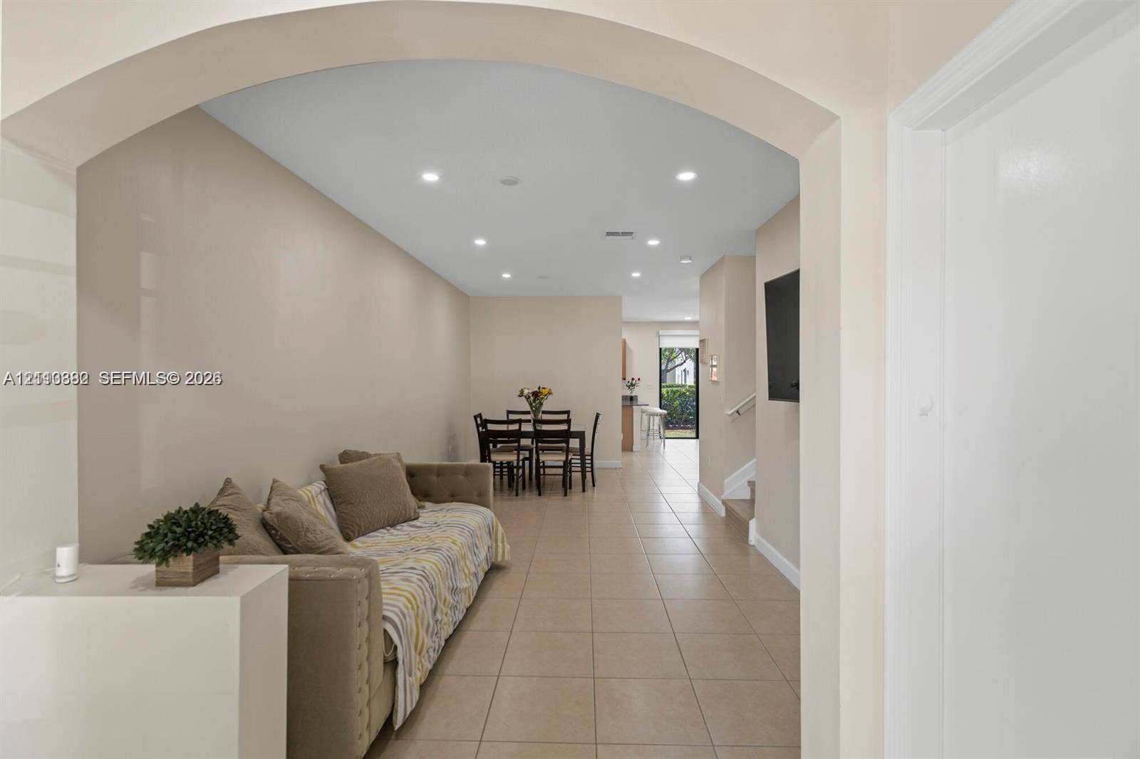 Interior space featuring a prominent arched architectural header, recessed ceiling lighting, and large-format tile flooring