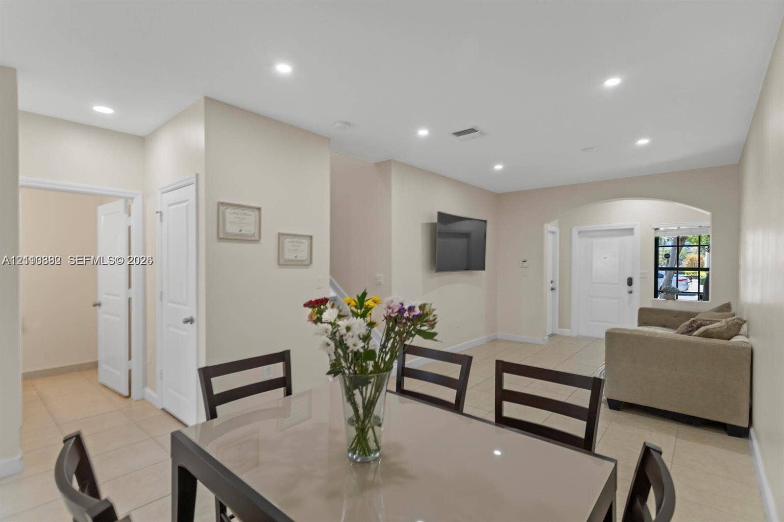 Open-concept area featuring neutral wall paint, tile flooring, recessed ceiling lighting, and an arched entryway