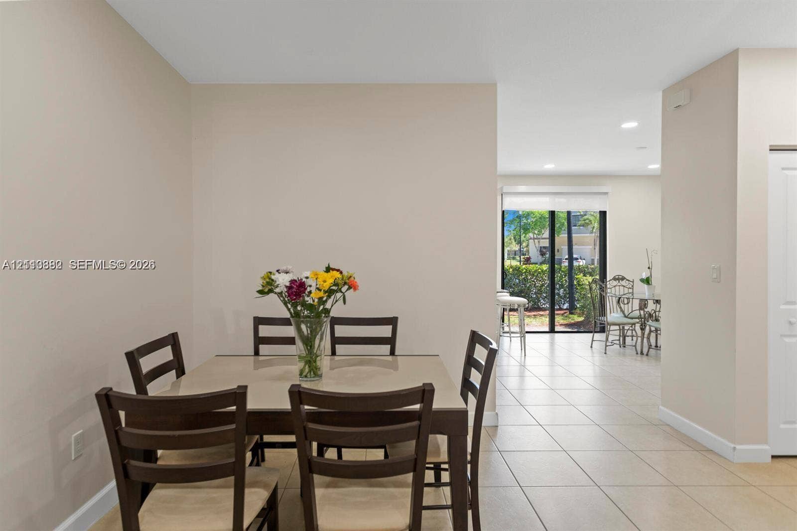 Neutral-toned interior featuring ceramic tile flooring, recessed ceiling lighting, and sliding glass doors with exterior access