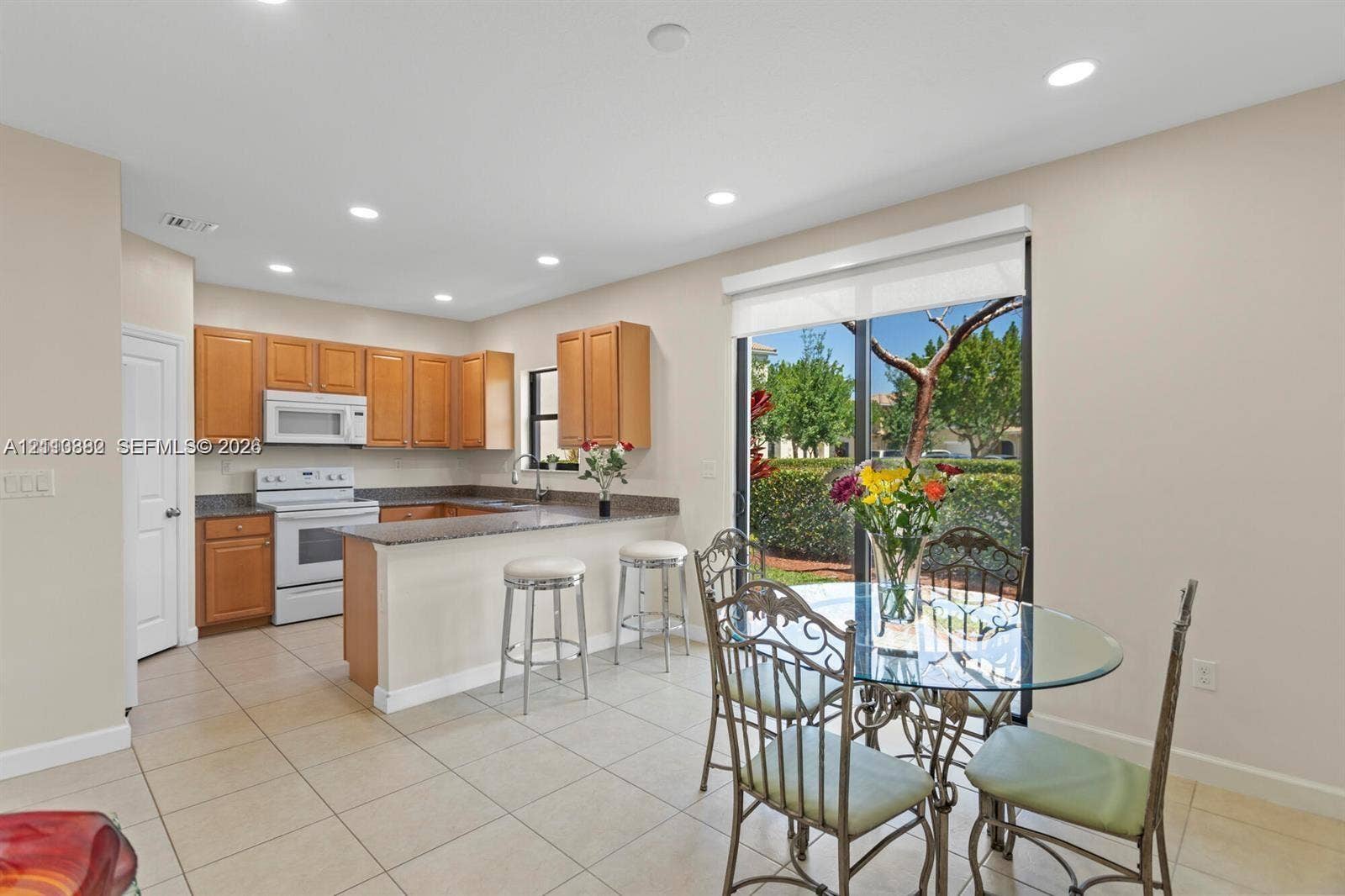 Kitchen featuring wood cabinetry, stone-finish countertops, recessed lighting, tile flooring, and a sliding glass door