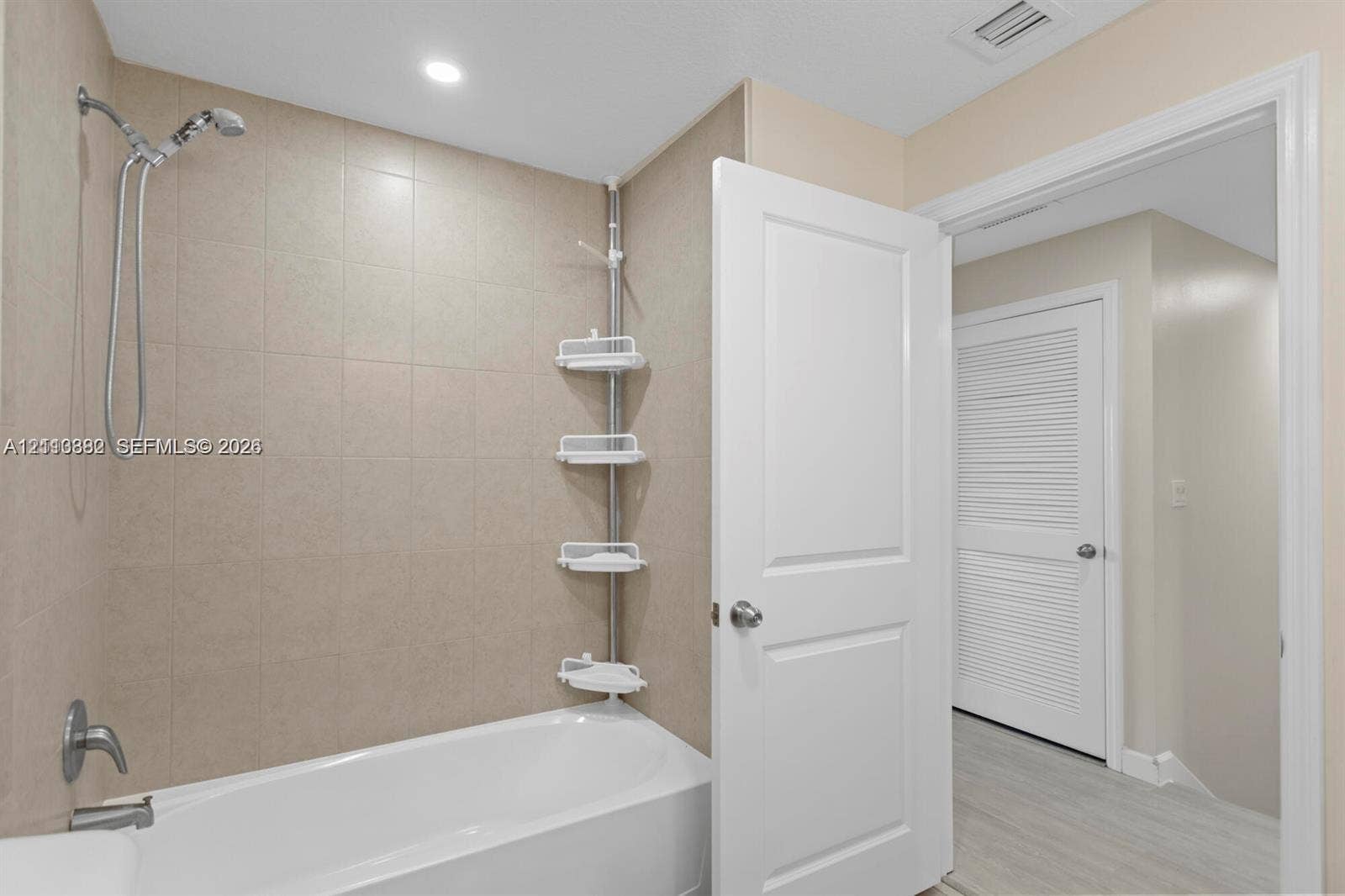 Full-height ceramic tile tub surround with integrated metallic faucet hardware and a recessed ceiling light
