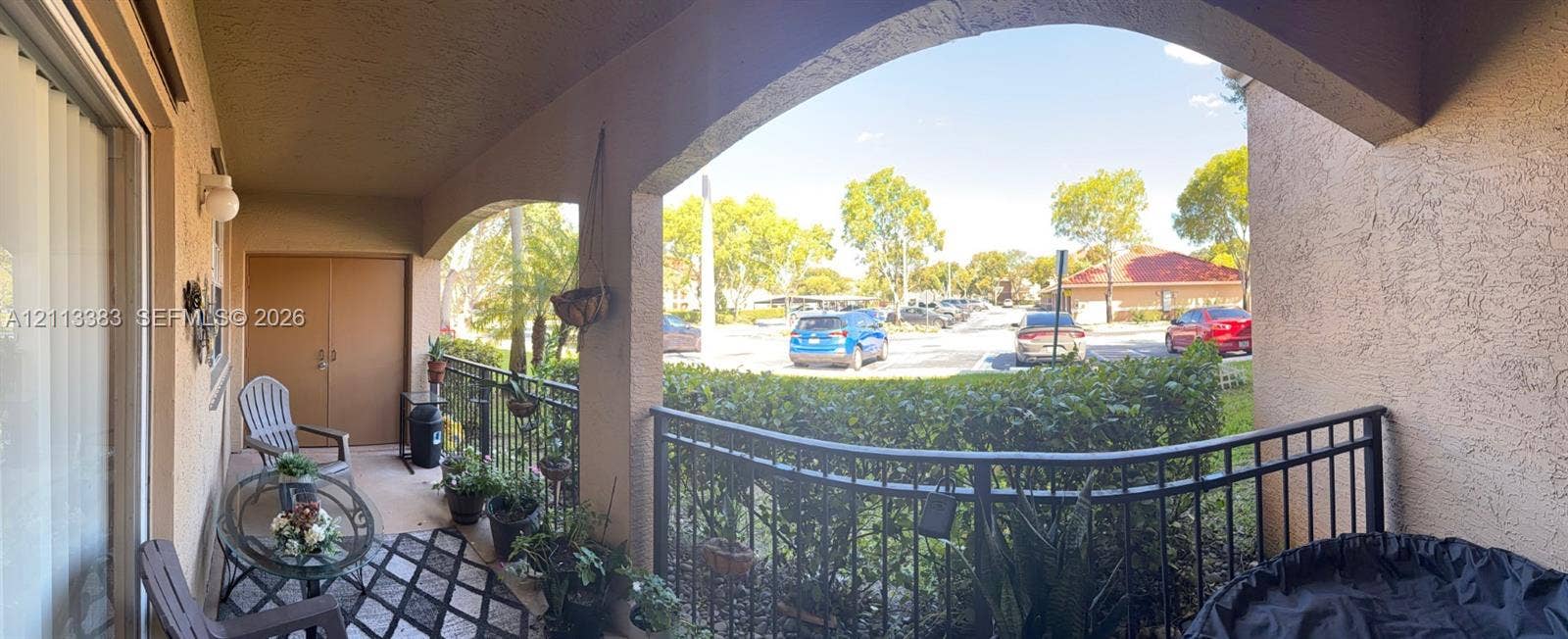 200 SW 117th Terrace, #10103, Pembroke Pines, FL 33025 Covered patio featuring arched structural supports, metal railings, a textured stucco exterior, and a built-in exterior storage closet