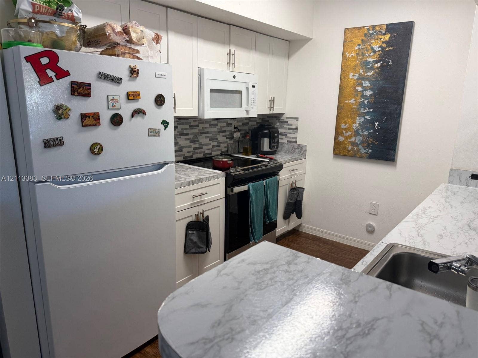 200 SW 117th Terrace, #10103, Pembroke Pines, FL 33025 Kitchen featuring white cabinetry, stone-finish countertops, tile backsplash, wood-finish flooring, and stainless steel sink