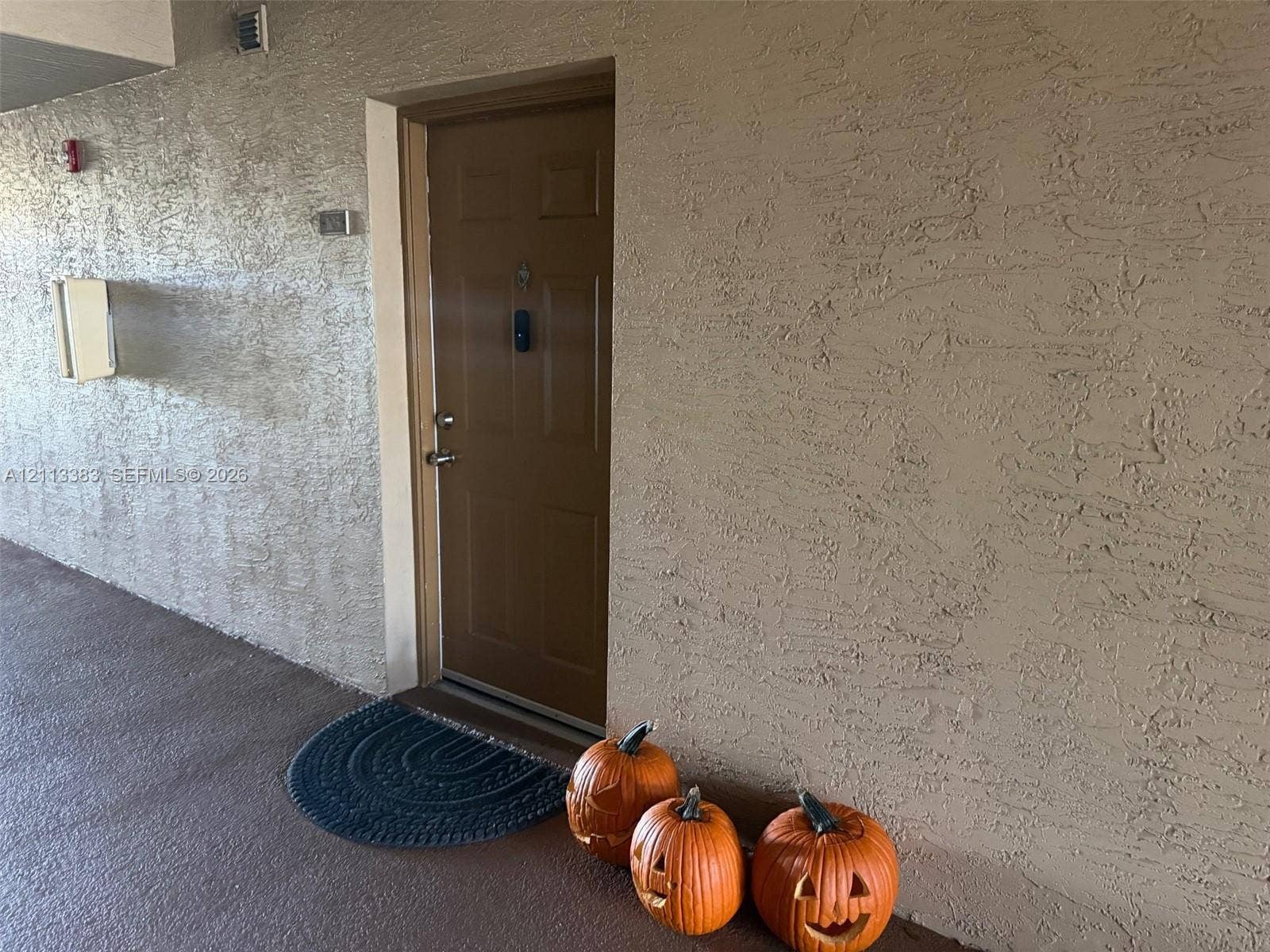 200 SW 117th Terrace, #10103, Pembroke Pines, FL 33025 Exterior entryway featuring a solid-panel door, textured stucco wall finish, and an integrated wall-mounted mailbox