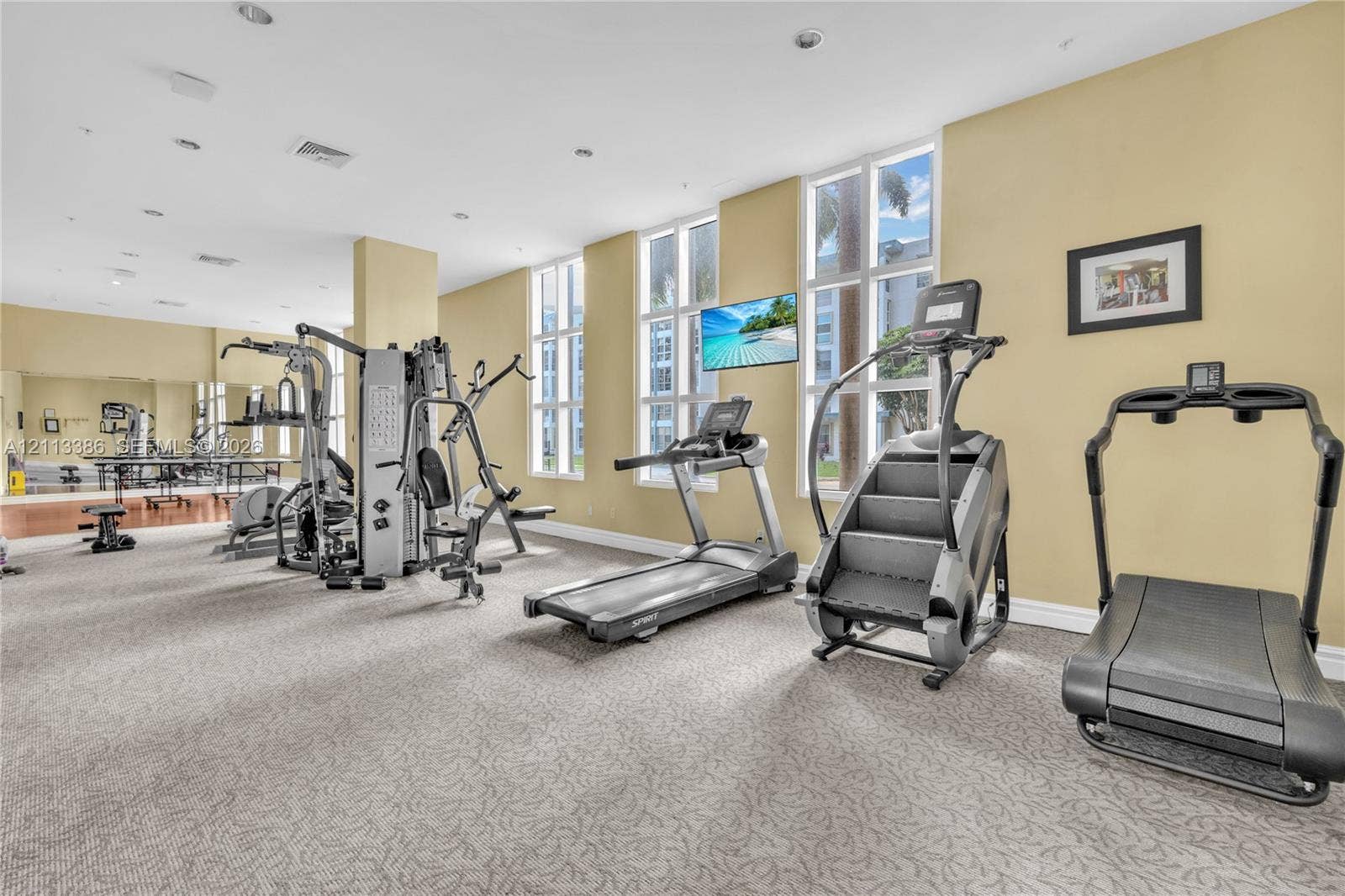 Fitness center featuring wall-to-wall mirrors, floor-to-ceiling windows, and recessed lighting