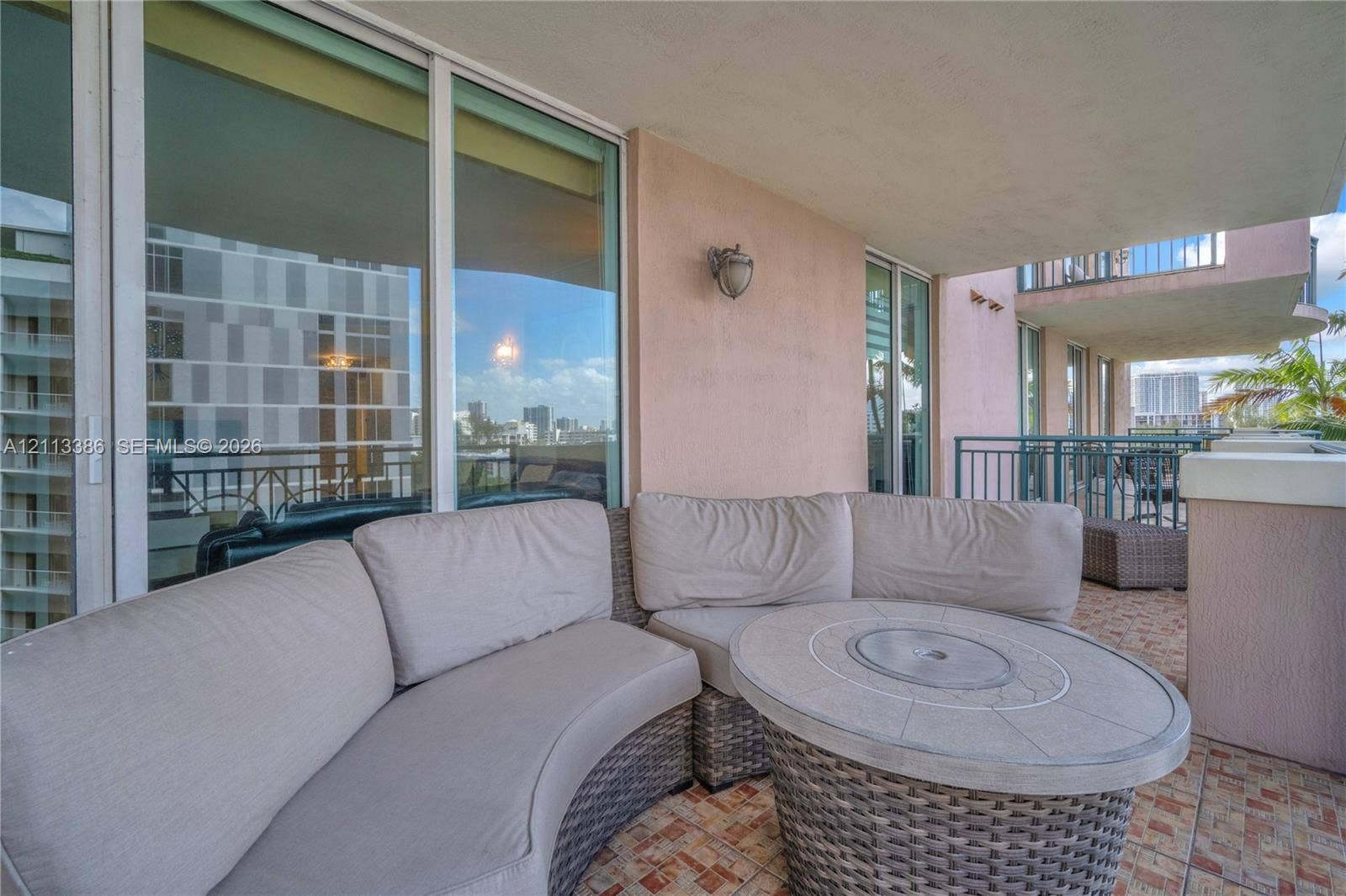 Covered balcony featuring floor-to-ceiling glass sliding doors, stone-tiled flooring, and metal railing