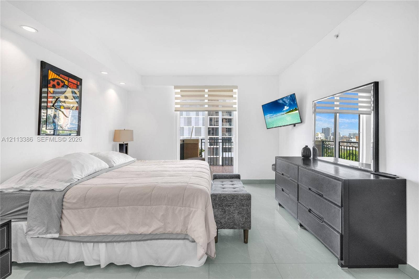 Neutral-toned tile flooring, recessed ceiling lighting, and sliding glass door with integrated window treatments opening to a balcony
