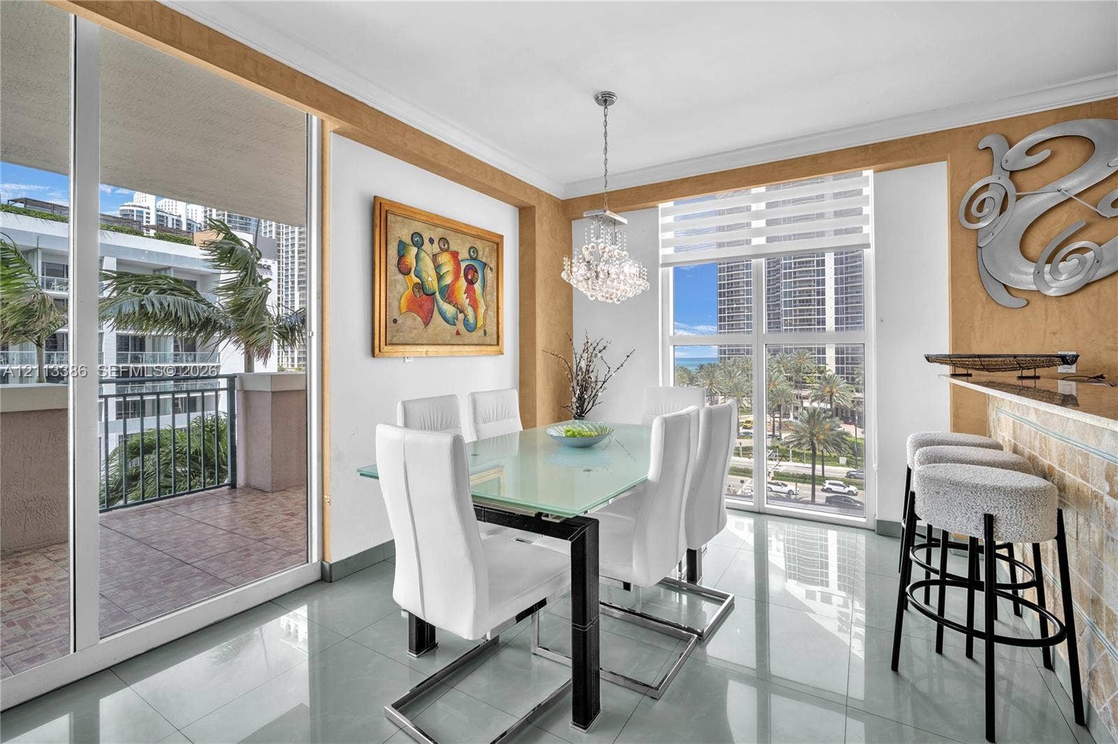 Dining area featuring polished tile flooring, floor-to-ceiling windows, a stone-accented breakfast bar, and a crystal chandelier
