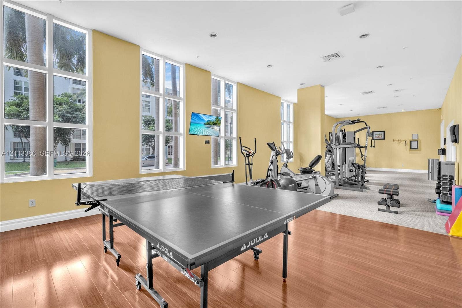 Fitness center featuring floor-to-ceiling windows, wood-finish flooring, and recessed ceiling lighting