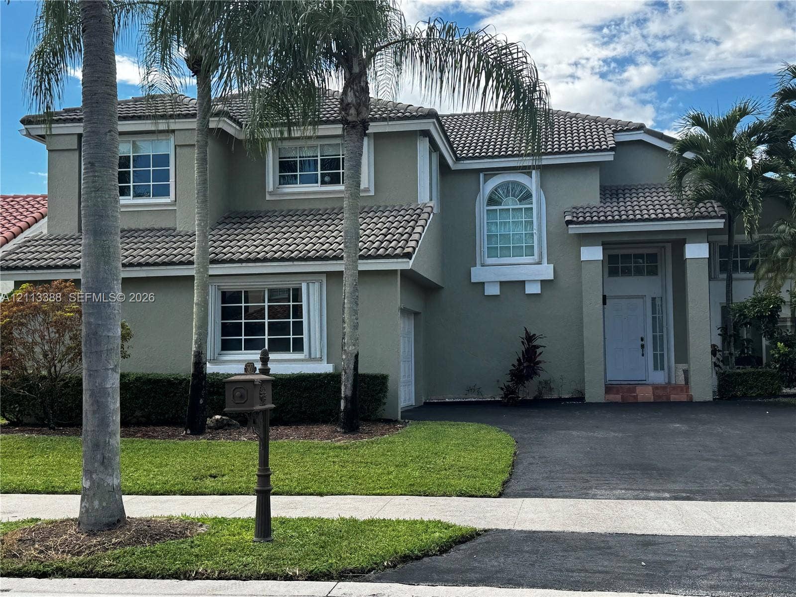 527 Water Point, Weston, FL 33326 Two-story stucco exterior featuring a multi-gabled tile roof, arched windows, and a paved driveway