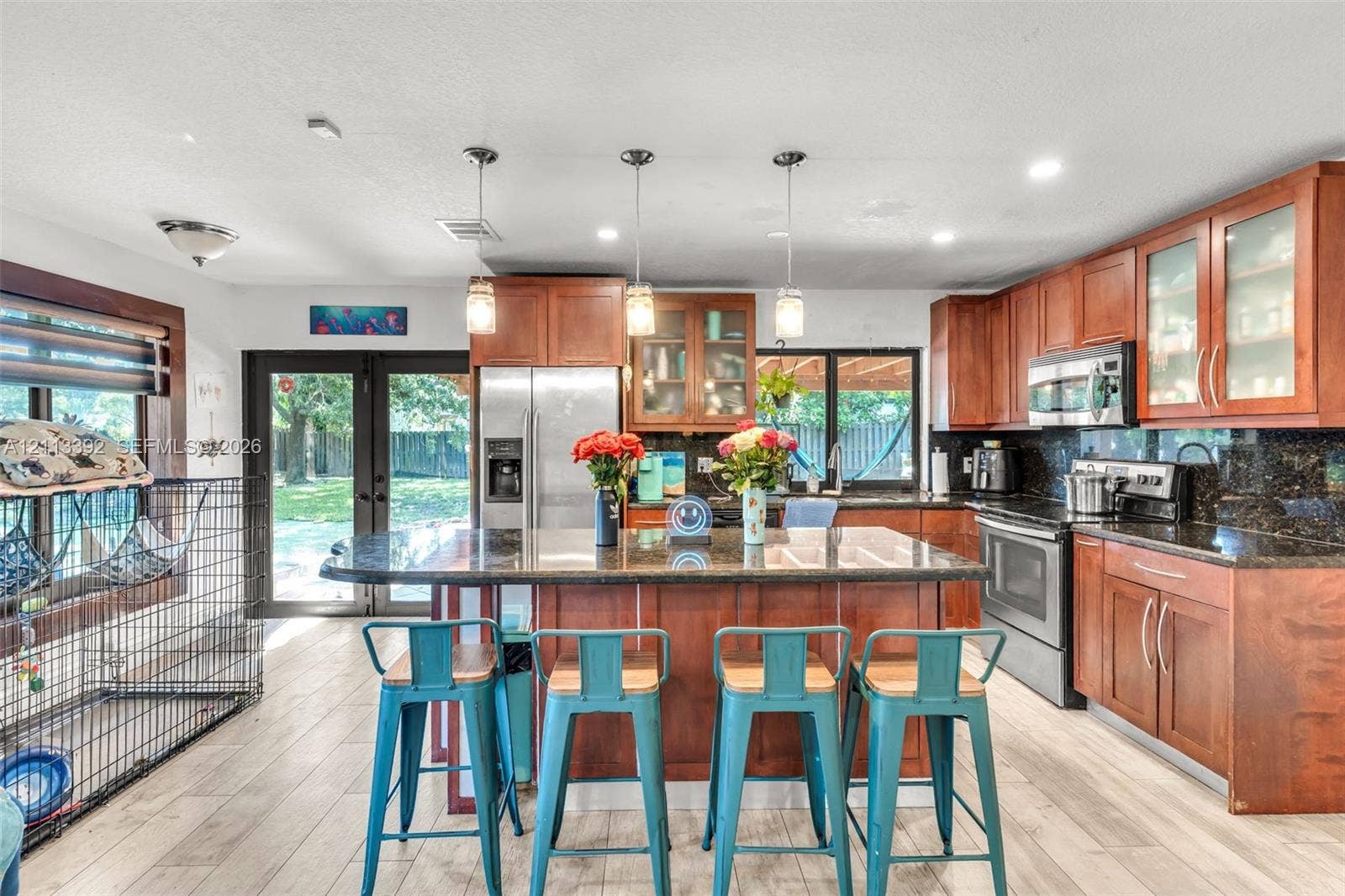 10705 SW 134th Court, Miami, FL 33186 Kitchen featuring wood cabinetry, stone countertops, a center island with pendant lighting, stainless steel appliances, and wood-finish flooring