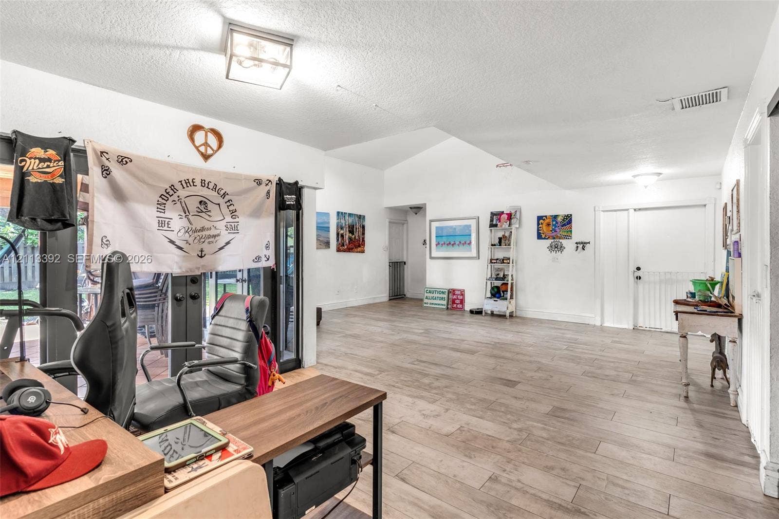 10705 SW 134th Court, Miami, FL 33186 Open floor plan featuring vaulted ceilings, wood-finish flooring, and multi-panel sliding glass doors