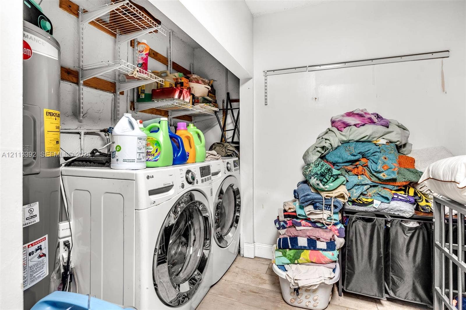 10705 SW 134th Court, Miami, FL 33186 Utility room featuring white front-load laundry appliances, a tall upright water heater, and wall-mounted metal shelving units