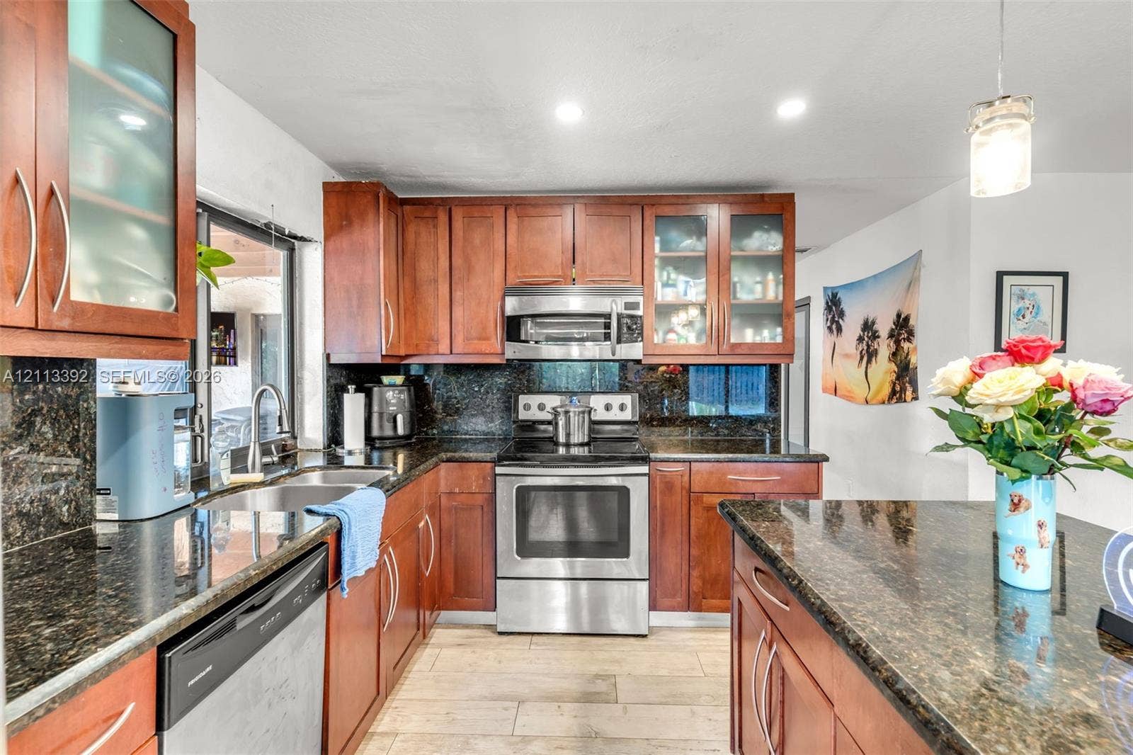 10705 SW 134th Court, Miami, FL 33186 Kitchen featuring custom wood cabinetry, dark stone countertops, stainless steel appliances, glass-front upper cabinets, and wood-finish flooring