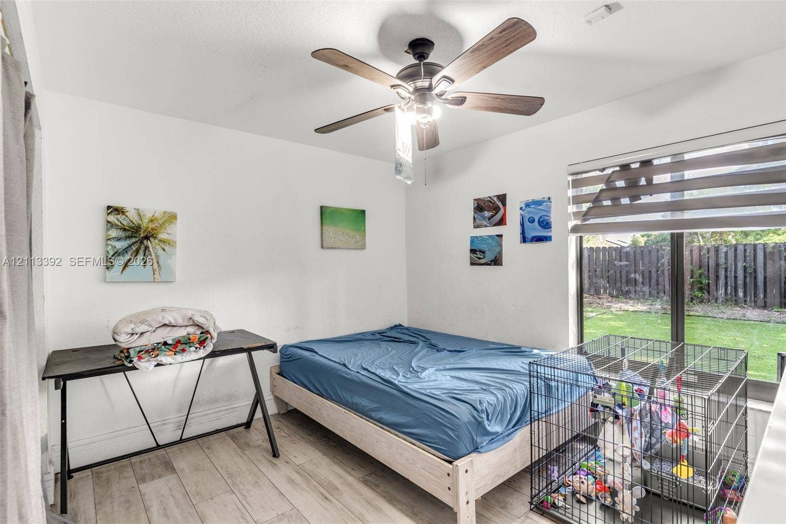 10705 SW 134th Court, Miami, FL 33186 Wood-finish flooring, ceiling fan with integrated lighting, and large window with dual-layer fabric shades