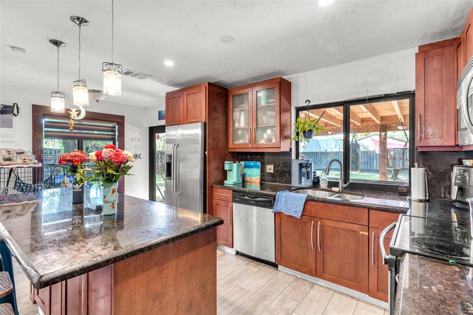 10705 SW 134th Court, Miami, FL 33186 Kitchen featuring a center island, wood-finish cabinetry, stone countertops, stainless steel appliances, and pendant lighting