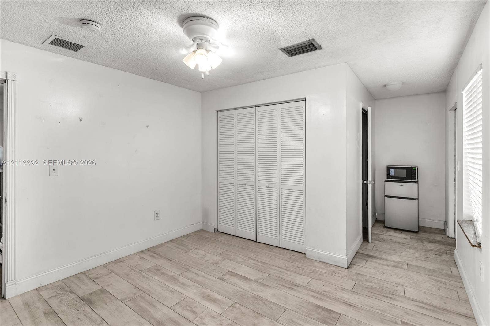 10705 SW 134th Court, Miami, FL 33186 Wood-finish tile flooring, ceiling fan with light fixture, and floor-to-ceiling closet with louvered doors
