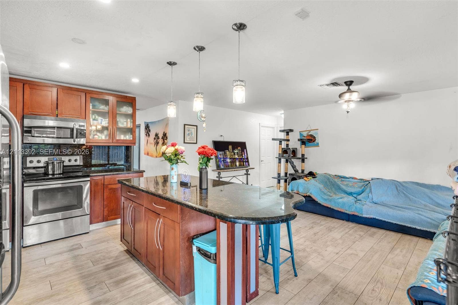 10705 SW 134th Court, Miami, FL 33186 Kitchen featuring wood-finish cabinetry, stone countertops, stainless steel appliances, pendant lighting, and wood-finish flooring