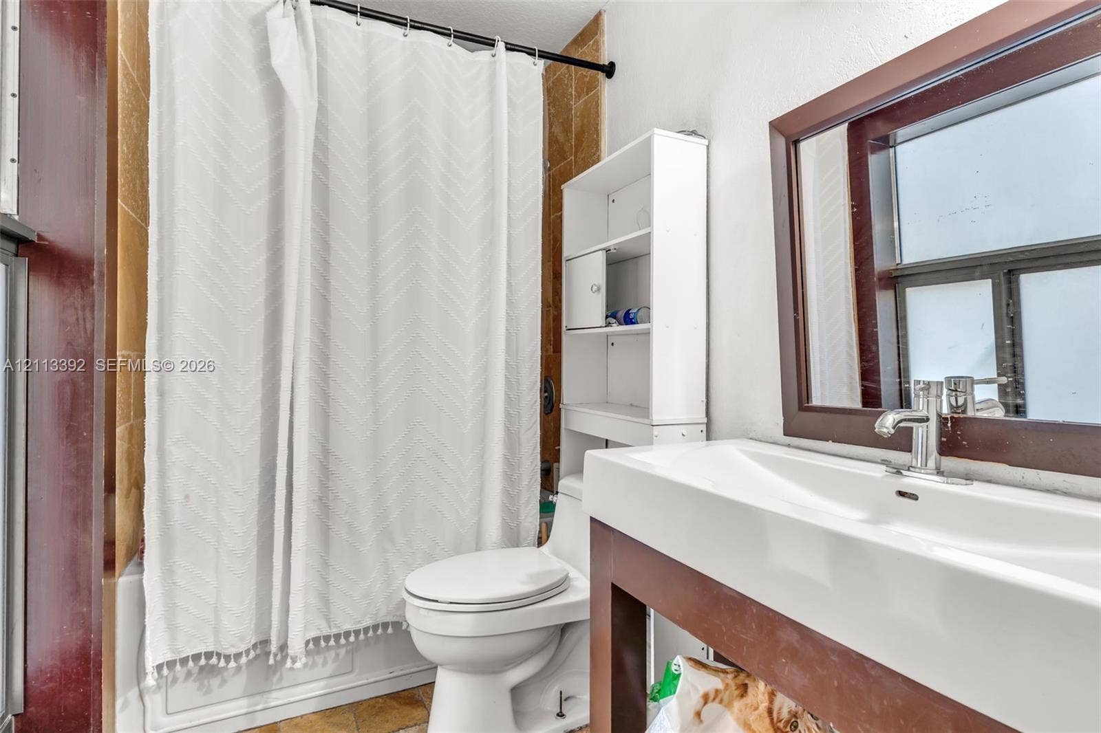 10705 SW 134th Court, Miami, FL 33186 Bathroom featuring a vanity with a rectangular sink, a metal faucet, a framed mirror, and a tub surround with tiled wall cladding