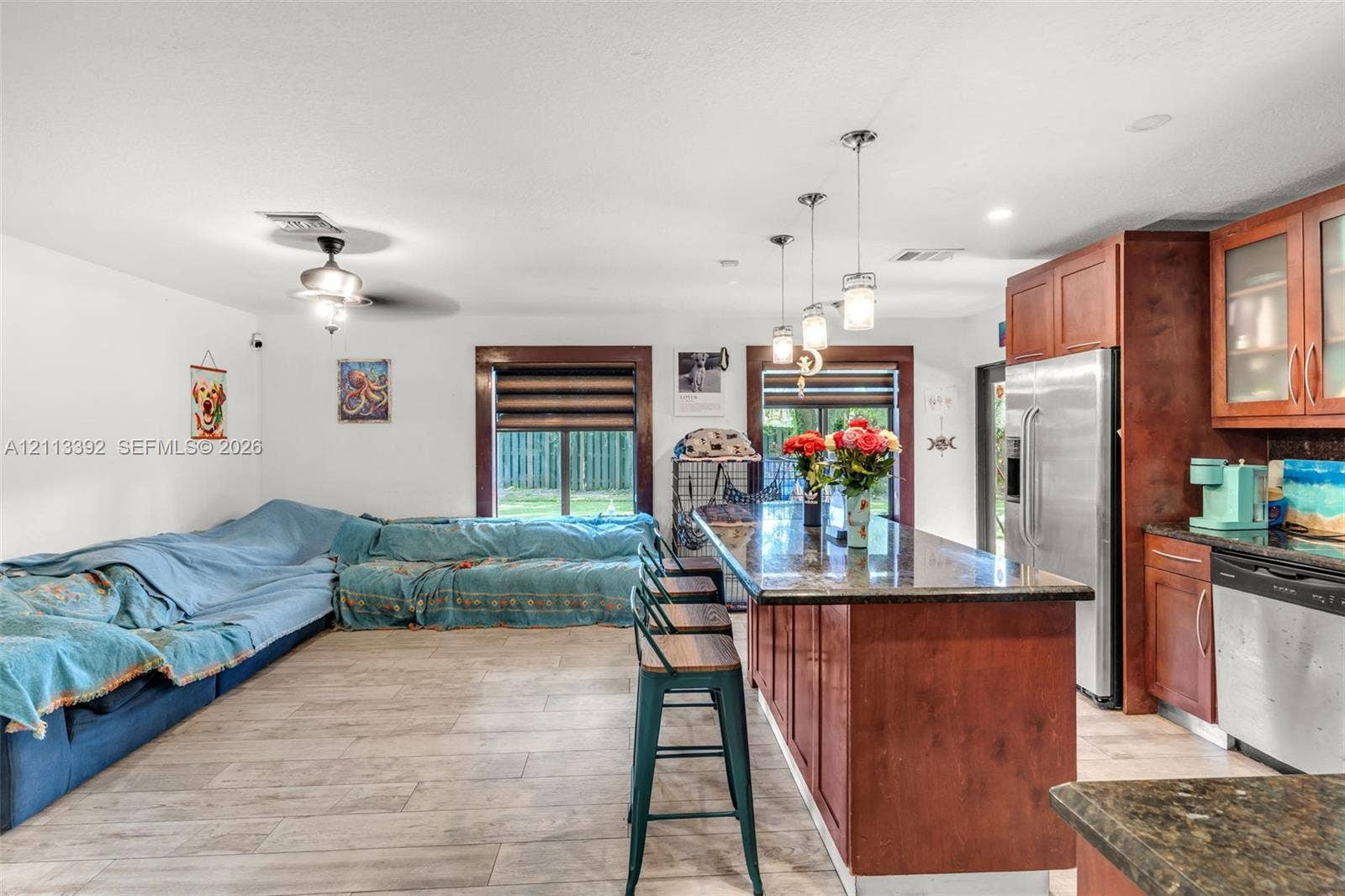 10705 SW 134th Court, Miami, FL 33186 Open-concept kitchen featuring stained wood cabinetry, stone countertops, stainless steel appliances, pendant lighting, and wood-finish flooring