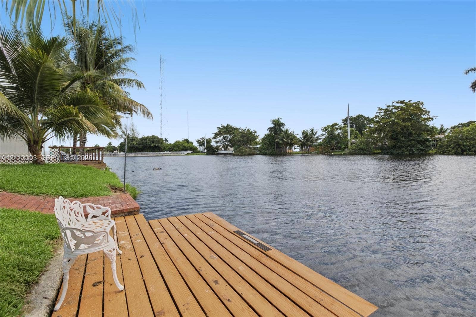 4136 SW 49th Street, Dania Beach, FL 33314 Waterfront lot featuring a wooden dock, brick paver pathway, and mature palm trees
