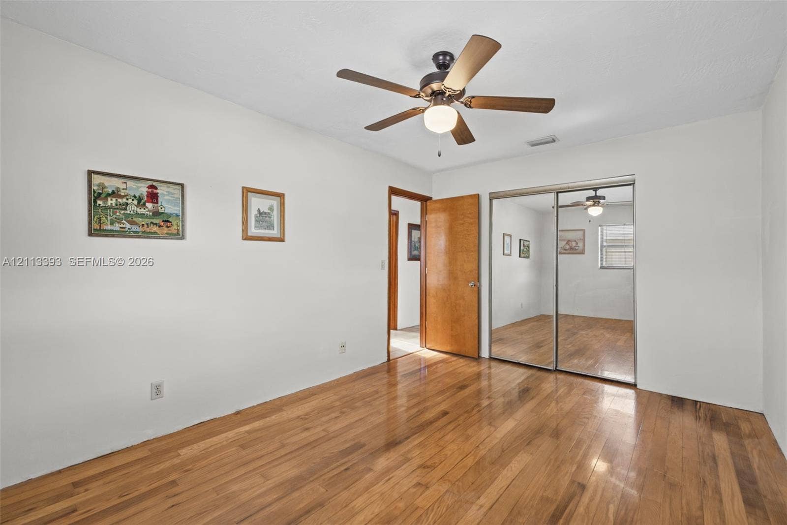 4136 SW 49th Street, Dania Beach, FL 33314 Wood-finish flooring, ceiling fan with integrated lighting, and mirrored sliding-door closet