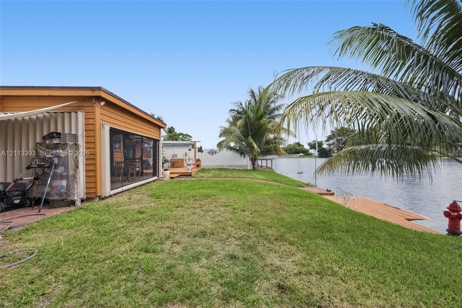 4136 SW 49th Street, Dania Beach, FL 33314 Waterfront property featuring a screened-in lanai, wood-finish siding, and a private wooden dock