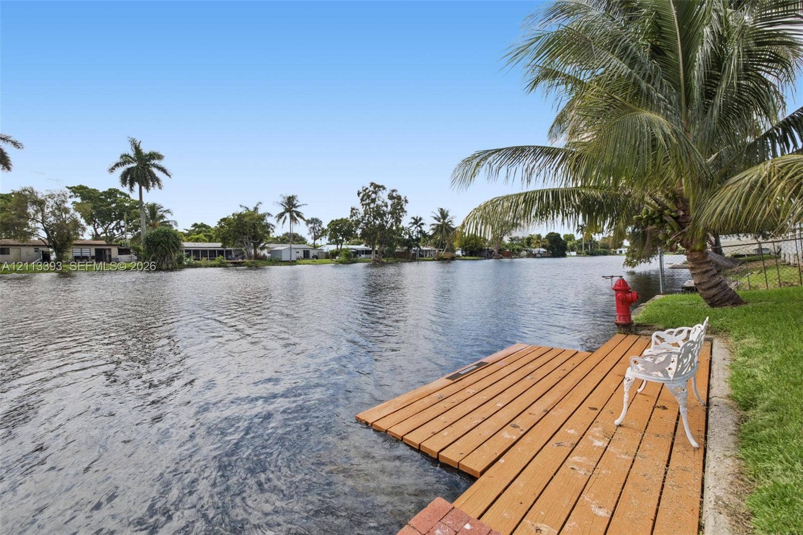 4136 SW 49th Street, Dania Beach, FL 33314 Waterfront property featuring a wood-plank dock, canal access, and mature palm trees