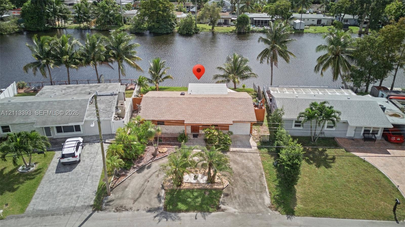 4136 SW 49th Street, Dania Beach, FL 33314 Waterfront property featuring direct canal access, a shingle roof, integrated garage, and mature palm landscaping