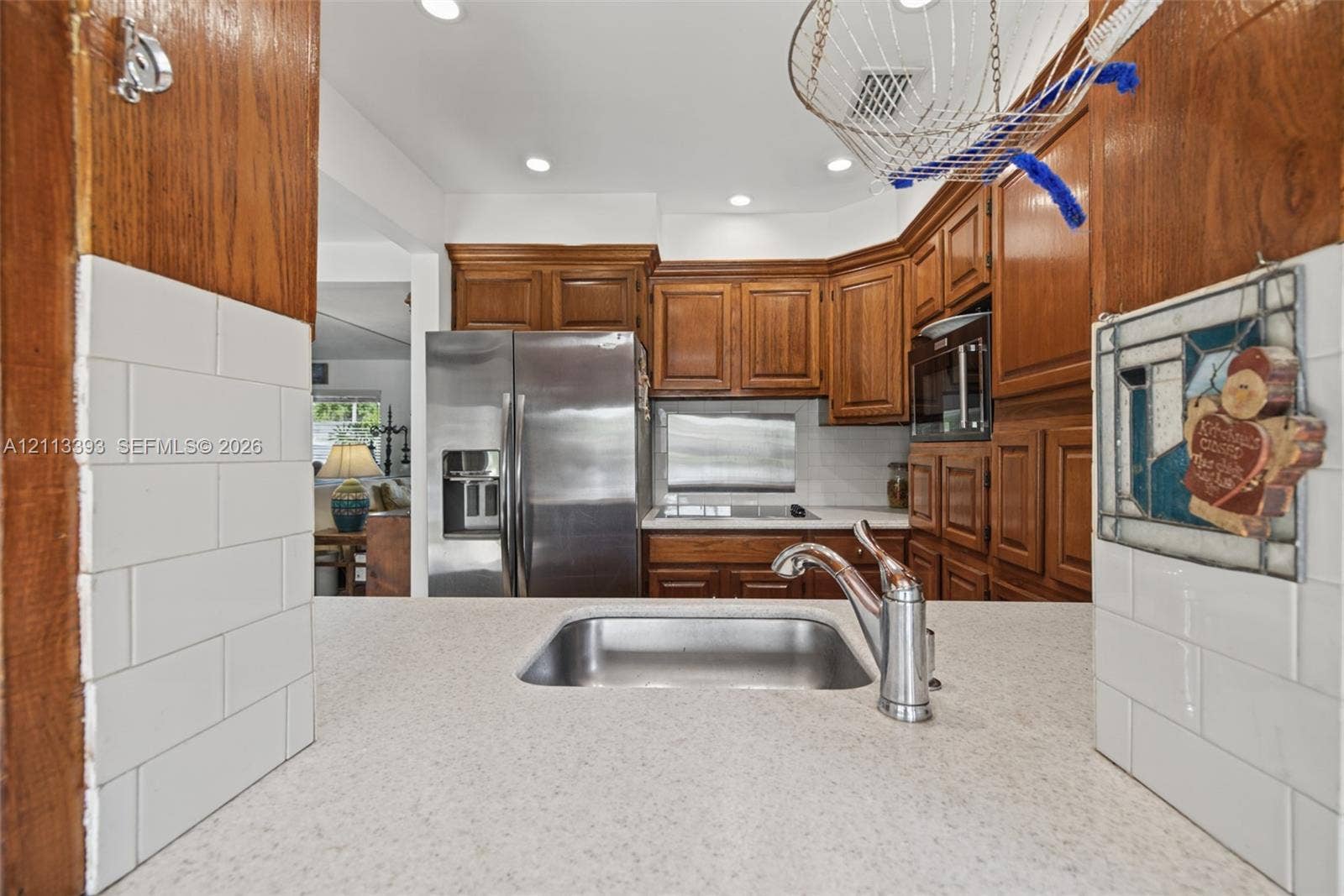 4136 SW 49th Street, Dania Beach, FL 33314 Kitchen featuring recessed lighting, medium-tone wood cabinetry, stainless steel refrigerator, white subway tile backsplash, and quartz countertop with a stainless steel undermount sink