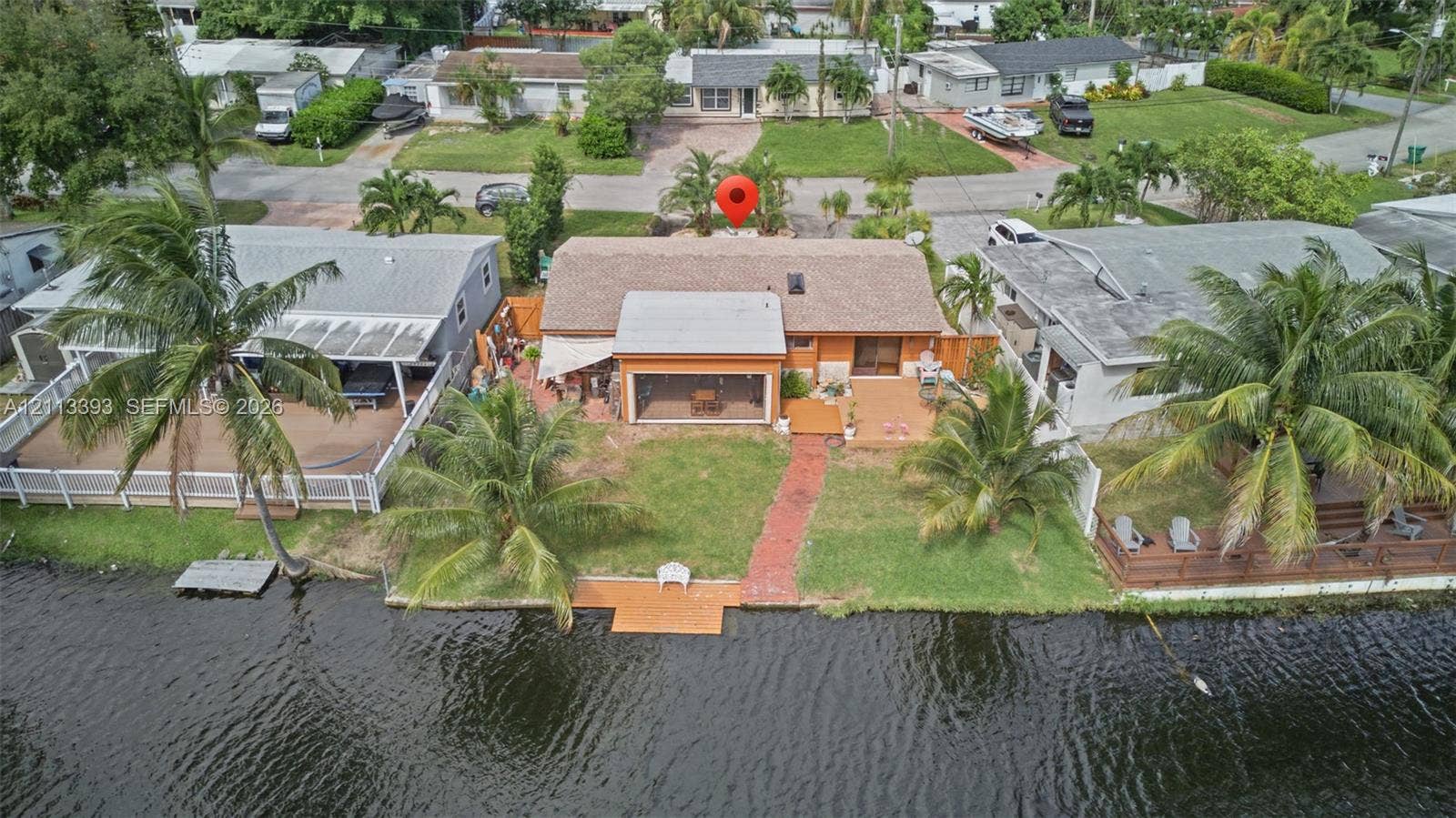 4136 SW 49th Street, Dania Beach, FL 33314 Waterfront property featuring a private dock, screened-in porch, brick-paver walkway, and mature palms