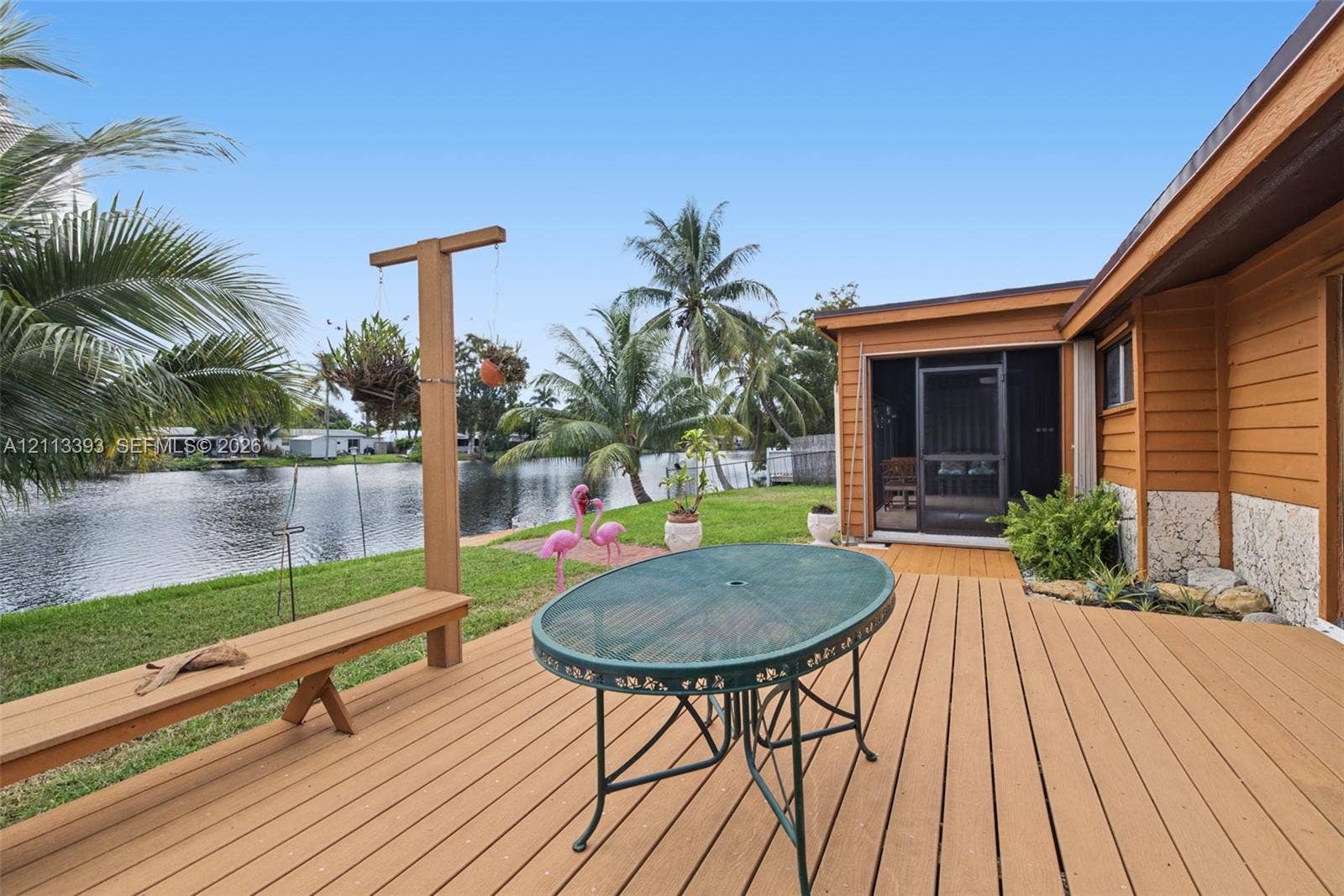 4136 SW 49th Street, Dania Beach, FL 33314 Waterfront outdoor space featuring a wood-finish deck, integrated bench seating, a screened-in porch, and direct bulkhead access