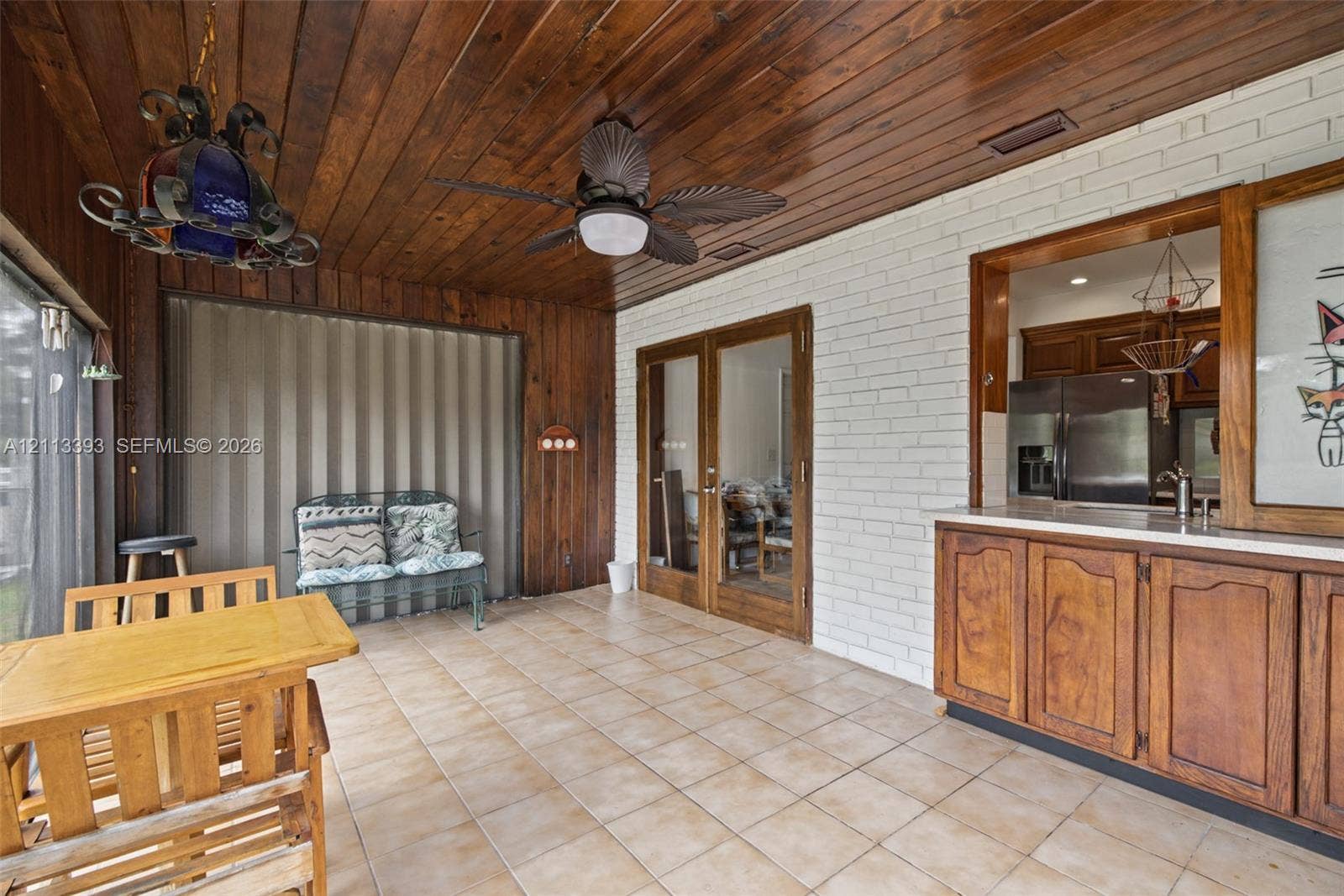4136 SW 49th Street, Dania Beach, FL 33314 Enclosed patio featuring wood-paneled ceiling, white-painted brick walls, tile flooring, built-in cabinetry with stone countertop, and glass-paneled double doors