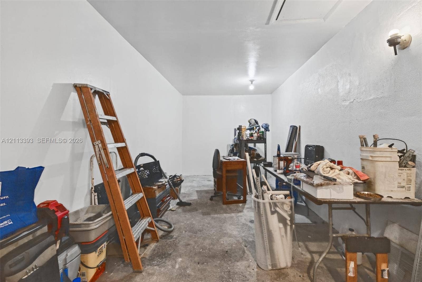 4136 SW 49th Street, Dania Beach, FL 33314 Enclosed storage area featuring white painted walls, a concrete floor, and dual wall-mounted light fixtures
