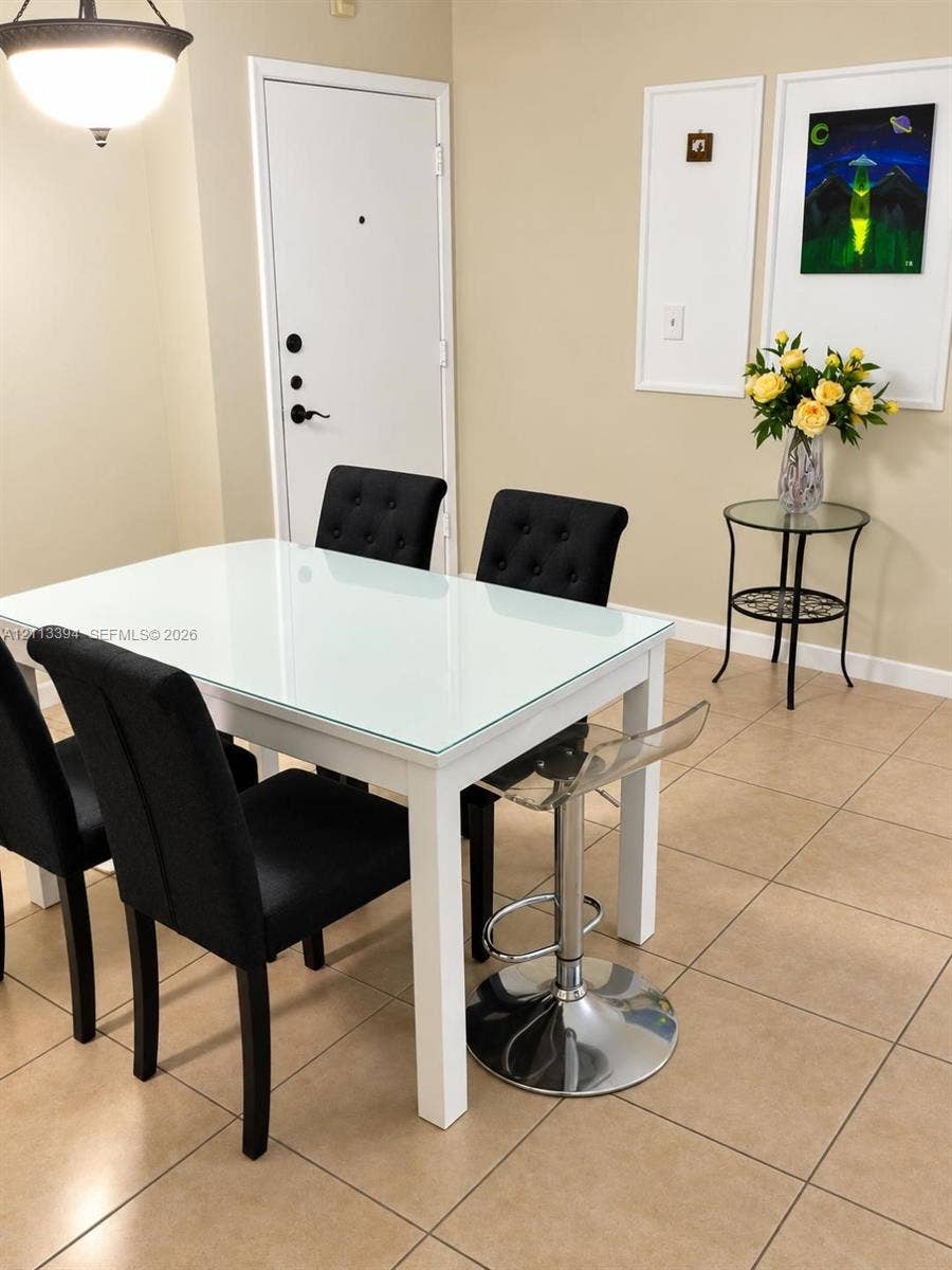 124 NE 19th Court, #108B, Wilton Manors, FL 33305 Neutral ceramic tile flooring, solid-core interior door with matte black hardware, and an architectural pendant light fixture
