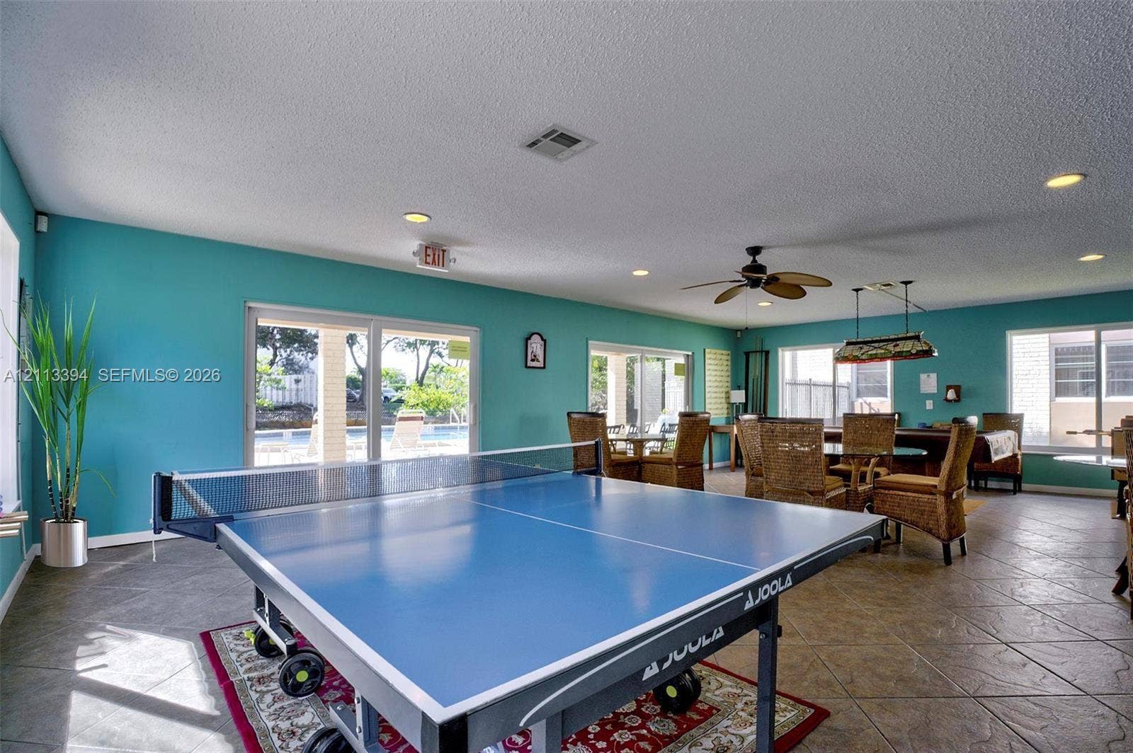124 NE 19th Court, #108B, Wilton Manors, FL 33305 Spacious interior featuring large-format tile flooring, recessed lighting, multiple sets of sliding glass doors, and a ceiling fan