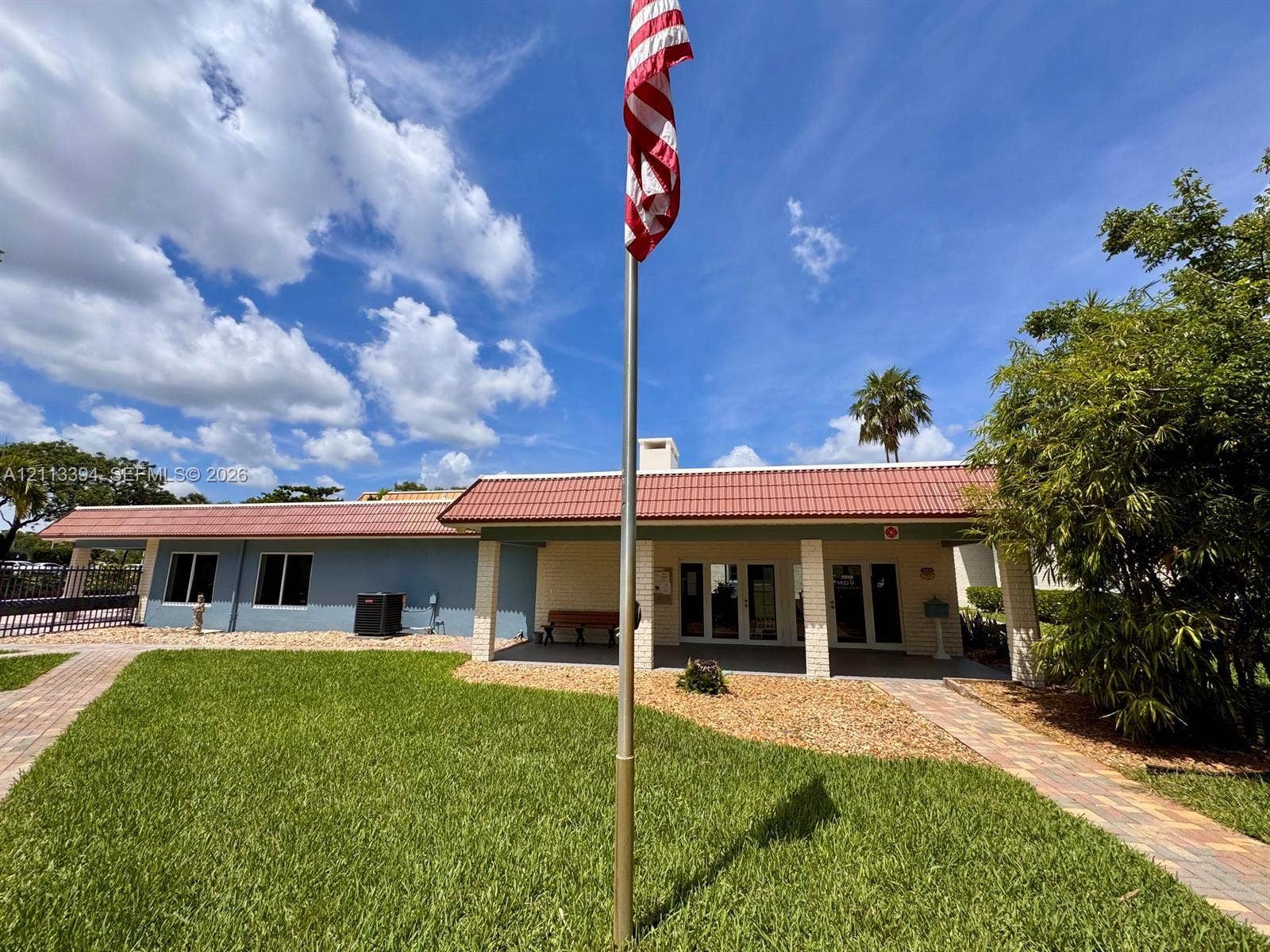 124 NE 19th Court, #108B, Wilton Manors, FL 33305 Exterior featuring a red tile roof, covered entryway with brick-style columns, paver walkways, and a manicured lawn